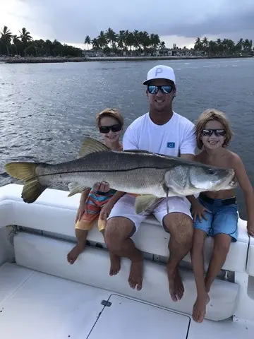 Family with a large snook caught aboard Tom Cat