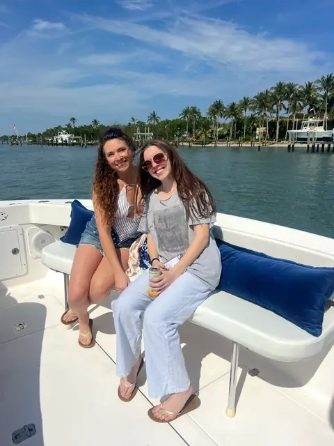 Two women smiling on Tom Cat's navy-cushioned bench seat on a sunny day on the Intracoastal