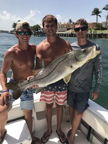 Three friends showing off a big snook caught on an inshore trip
