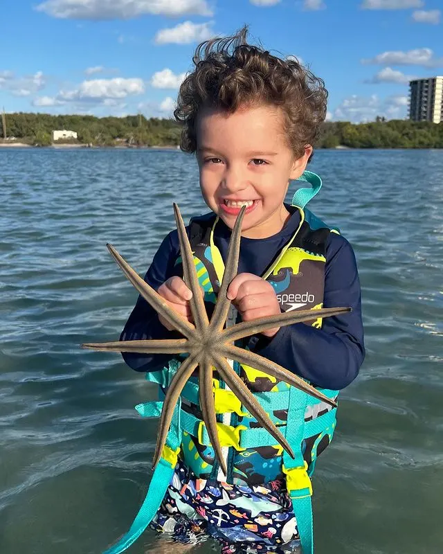 Smiling boy holding a starfish during a snorkel stop